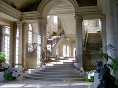 an ornate staircase in the middle of a building with large windows and stone steps leading up to it