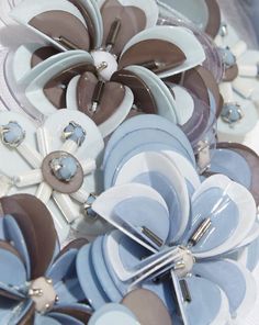 a bunch of blue, brown and white flowers with silver pins on it's centers