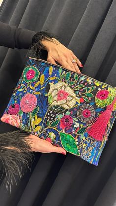 a woman is holding a colorful clutch bag