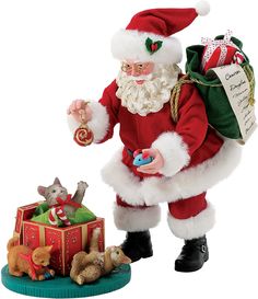 a santa clause figurine holding a christmas ornament next to his presents