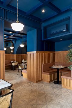 an empty restaurant with blue walls and wooden booths