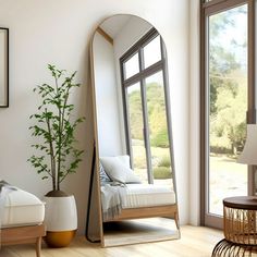 a large mirror sitting on top of a wooden floor next to a bed in a room