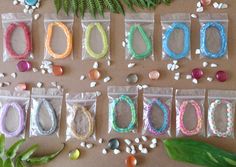 there are many different bracelets on the table next to some plants and rocks in plastic bags