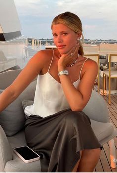 a woman sitting on top of a gray couch next to a white table and chair