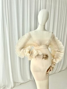 a mannequin wearing a white dress with ruffles on the sleeves and bottom