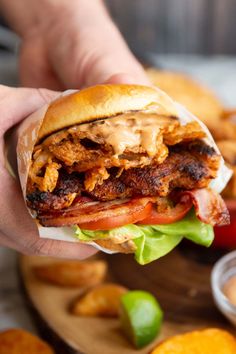 a person is holding up a sandwich with meat and lettuce in front of some french fries