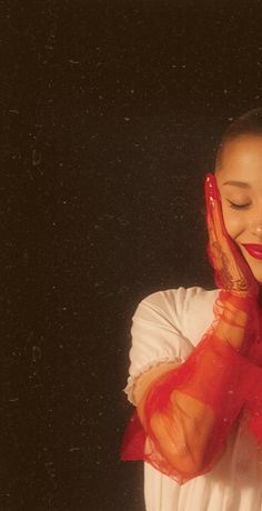 a woman holding her hands up to her face and wearing a red scarf around her neck