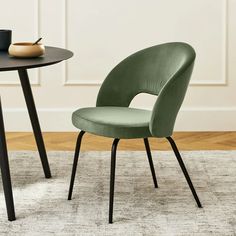 two chairs sitting on top of a rug next to a table with a cup and saucer