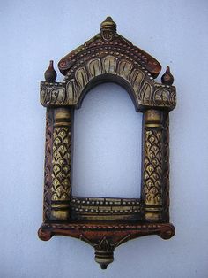 an ornate wooden frame with birds on it against a white wall, in the shape of a window