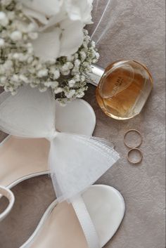 a bouquet of white flowers next to two pairs of shoes and a bottle of perfume