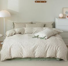 a bed with white sheets and pillows in a room next to a lamp on the floor