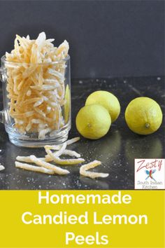 homemade candied lemon peels in a glass jar next to two lemons on a counter