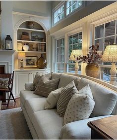 a living room filled with lots of furniture next to a window covered in bookshelves