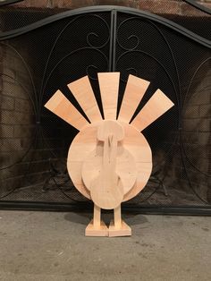 a wooden turkey standing in front of a fire place with an iron fireplace screen behind it