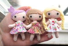 three little dolls are sitting on someone's hand