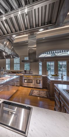 a large kitchen with stainless steel appliances and wood flooring on the walls is pictured in this image