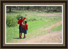 a woman and child walking down a dirt road