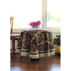 a table with a flower vase on top of it next to a chair and window