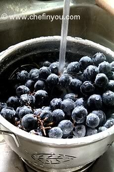 blueberries are being washed in a pot on the stove top with water pouring from a faucet