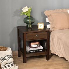 a night stand with books and a vase on it