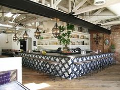 the bar is decorated with black and white checkerboard tiles, hanging lights, and potted plants