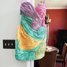 a multicolored piece of cloth hanging on the wall next to a dining room table