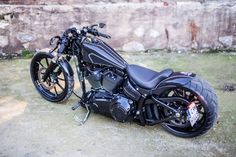 a black motorcycle parked next to a stone wall