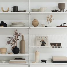 the shelves are filled with vases, books and other decorative items in white shelving