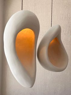 two white vases hanging from strings in a room