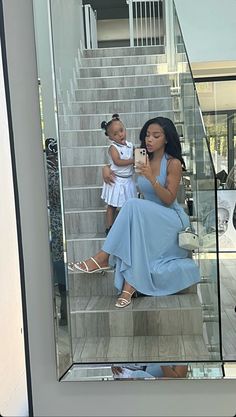 a woman taking a selfie with her daughter on the stairs in front of a mirror