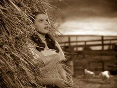 an old photo of a woman standing next to a hay pile with birds in the background