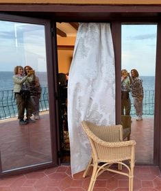 a chair sitting in front of a glass door on top of a brick floor next to the ocean