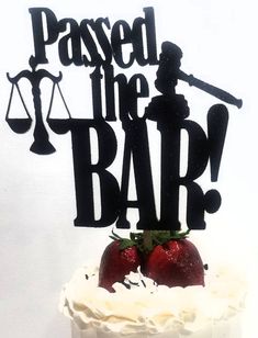 a cake with the words passed the bar on it and two strawberries sitting on top