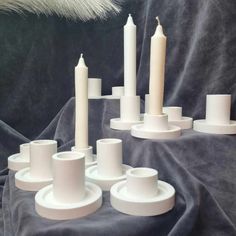 several white candles are arranged on a gray blanket