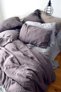 an unmade bed with several pillows on it