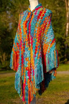 a colorful crocheted shawl draped over a mannequin