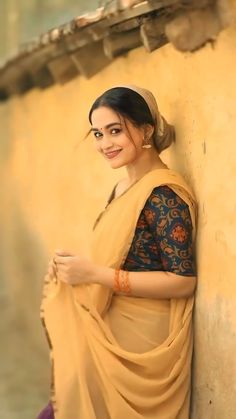 a woman wearing a sari standing next to a wall