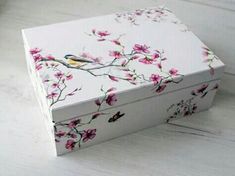 a white box with pink flowers and a bird on it