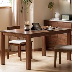 a wooden table with two chairs and a laptop on it