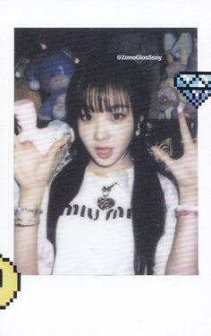 a girl with long black hair wearing a white shirt and holding her hands up in front of her face