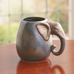 an elephant shaped vase sitting on top of a wooden table