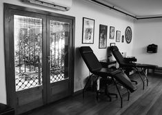 black and white photograph of chairs in front of glass doors with pictures on the wall