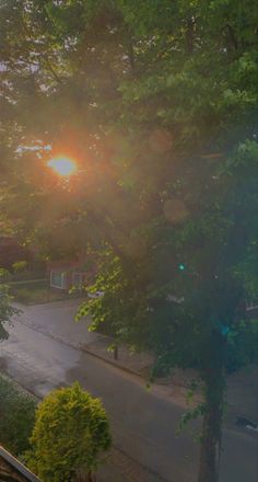 the sun shines brightly through the trees in front of an apartment building on a rainy day