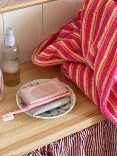 a pink and orange towel sitting on top of a table next to a plate with toothbrushes