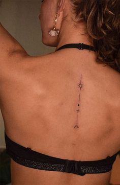 the back of a woman's neck with a cross tattoo on her left side