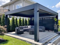 an outdoor living area with couches and tables in the foreground, next to a house