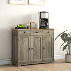 a coffee maker on top of a wooden cabinet next to a potted plant