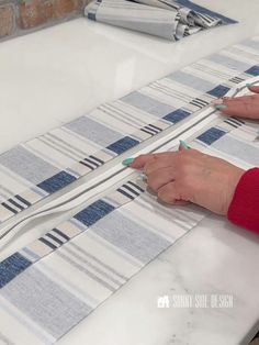 a woman is cutting fabric with scissors on a table