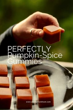 a person holding a piece of pumpkin spice on top of a metal pan with the words perfectly pumpkin spice gummies