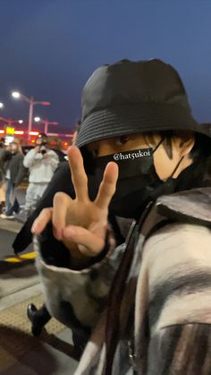 a person wearing a black hat making the peace sign